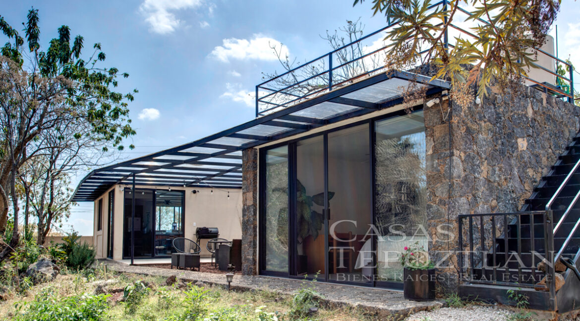 Hermosa_casa_de_piedra_con_gradnes_ventanales_bardeada_privada_con_estacionamiento_para_varios_autos_frente